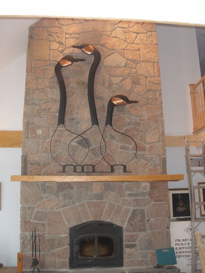 Wrought iron goose sculptures above stone fireplace