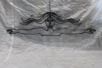 Woman's face with flowing hair in wrought iron