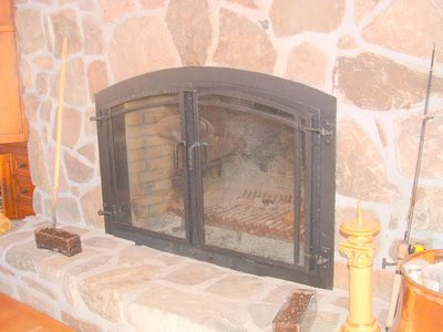 Arched wrought iron fireplace screen on stone fireplace
