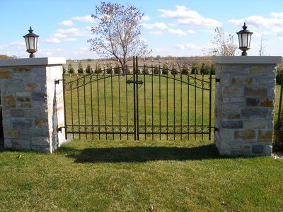 Wrought iron entry gate with stone pillars