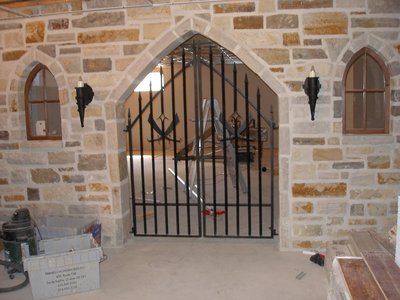 Gothic wrought iron gate in stone arch with wall sconces