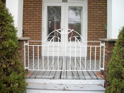 White wrought iron porch gate with scrollwork