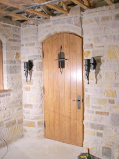 Arched wooden door with wrought iron hardware and wall sconces