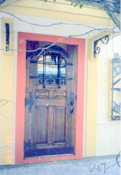 Door with arched wrought iron grille and decorative hinges