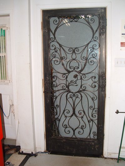 Wrought iron door grille with scrollwork and floral motifs