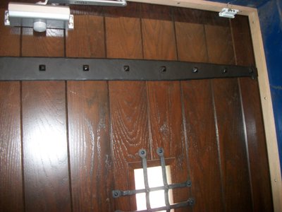 Wooden door with wrought iron strap hinges and grate