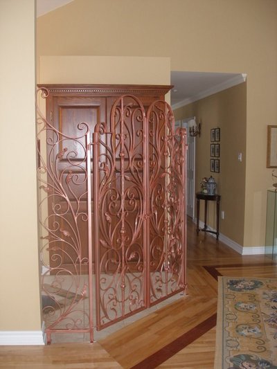 Copper-toned wrought iron wine cellar gates with vine motifs